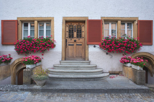 Wooden door and windows with red shutters and flowers in Murten