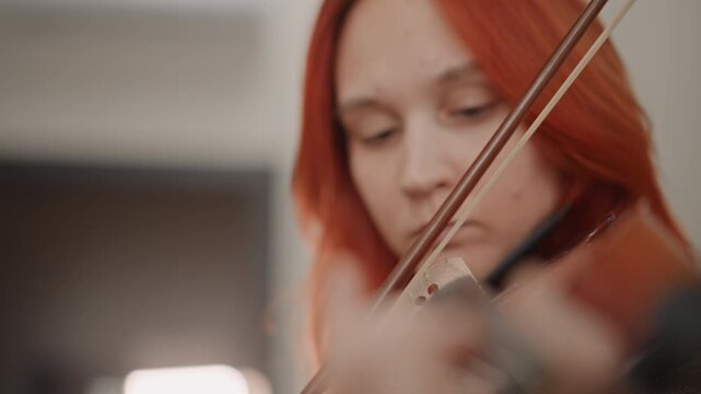 Caucasian violin student focused audition rehearsal, closeup portrait with intense gaze, red hair framing face, precise bowing motion and finger placement, studio lighting, visible determination