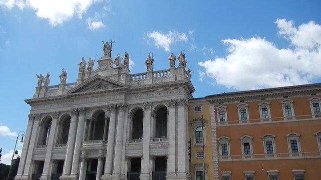 Facade of Basilica of St. John in Lateran in Rome i Italy with statues of Lord Jesus Christ and saints, loggia of blessings and blue sky with slowly moving white clouds. Topics: church, Christianity
