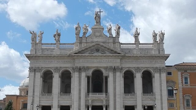 Facade of Basilica of St. John in Lateran in Rome i Italy with statues of Lord Jesus Christ and saints, loggia of blessings and blue sky with slowly moving white clouds. Topics: church, Christianity