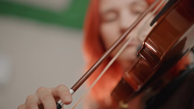 Violin bow close up redhead musician, expressive bowing scenes capture dynamic contact between horsehair and strings, soft classroom light, concentrated performance and tonal control
