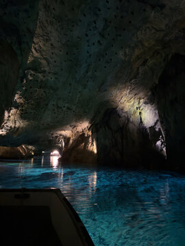 Saint-L&eacute;onard, Valais, Switzerland - May 02, 2026: Wooden Boat Crossing the Turquoise Still Waters of the Underground Cave Lake at Lac Souterrain