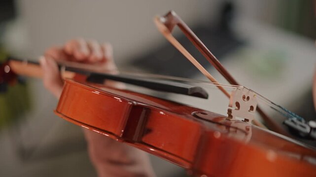 Detailed bowing technique on violin strings, closeup of bow stroke and hand coordination, slow deliberate motion showing dynamics and articulation, practice session with focused coachlike instruction
