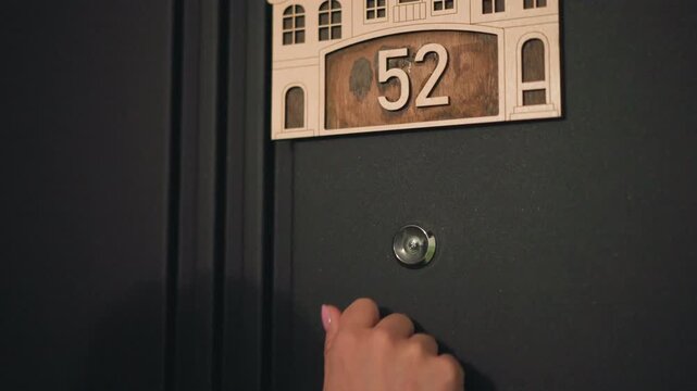Paramedic knocking on apartment door, dim hallway lit by soft corridor light, hand tapping near peephole, brass plaque showing number, nighttime home visit during emergency response, medic and nurse