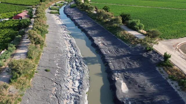 Aerial view of the rio Segura riverbed restoration using plastic covers on the banks to eradicate the invasive Arundo donax giant reed protecting the agricultural landscape ecology in murcia orihuela