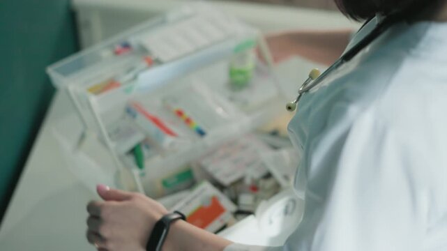 Emergency responder inspecting medical response kit, clear plastic case opened to reveal vials, bandages, oxygen mask and labeled compartments, focused hands performing readiness check