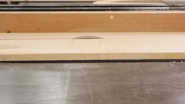 Woodworker uses a shop-made push shoe to rip narrow maple face frame stock on a table saw. Close-up of ripping technique in a cabinet shop.
