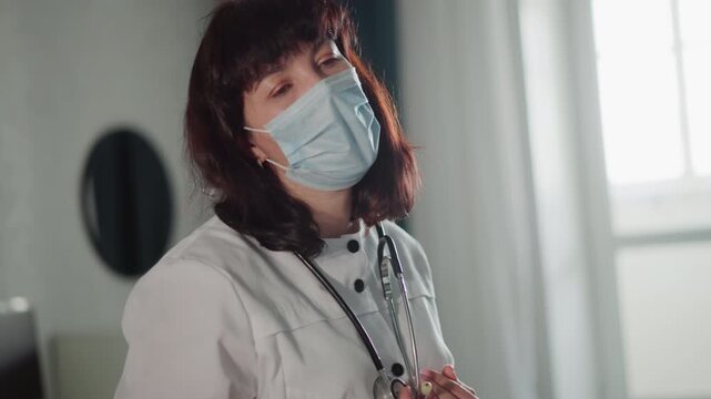 White doctor wearing mask readying stethoscope, clinical gaze through mask, protective PPE, telemedicine and inperson care hints, empathetic expression visible in eyes, gentle lighting