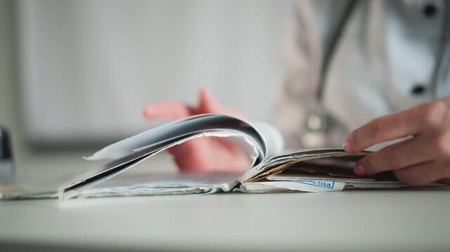 Registration handling in busy office. Detailed view of healthcare worker sorting forms swiftly at desk. Caring professional methodically managing patient forms during busy administrative day