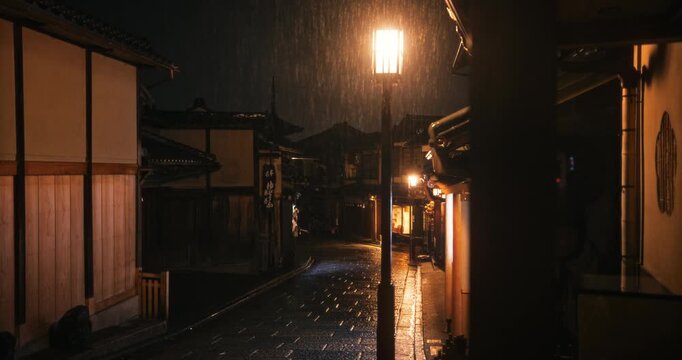 Rain fall on ancient, empty Japanese village street at night - tracking, wide shot