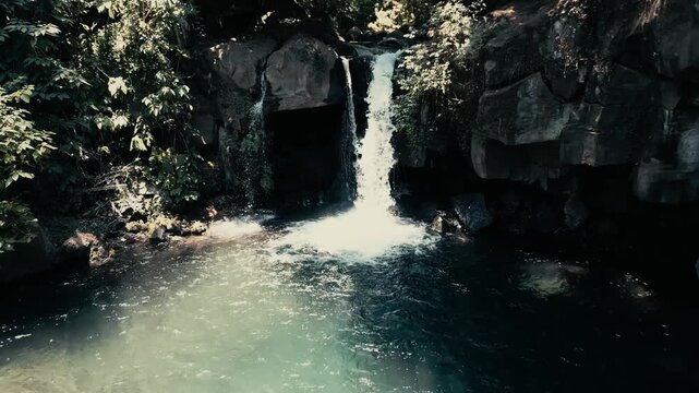 Drone footage establishing shot facing a cinematic waterfall hidden in the tropical jungle