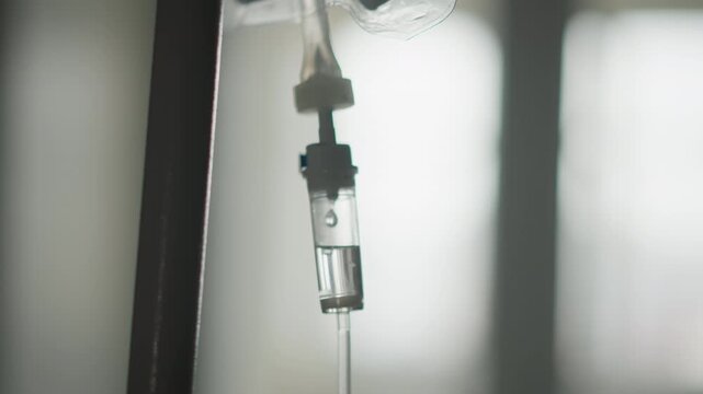 Closeup of fluid passing through chamber with soft backlighting focus. Highresolution depiction of transparent fluid flowing through chamber and tubing against illuminated background