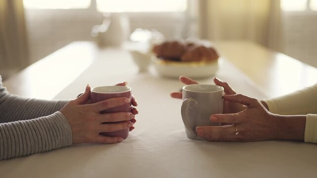 Close-up of two women friends talking and drinking tea at home