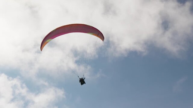 People try paragliding flying with parachutes against clouds