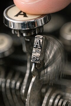 A close-up shot of a person's finger typing on an old typewriter