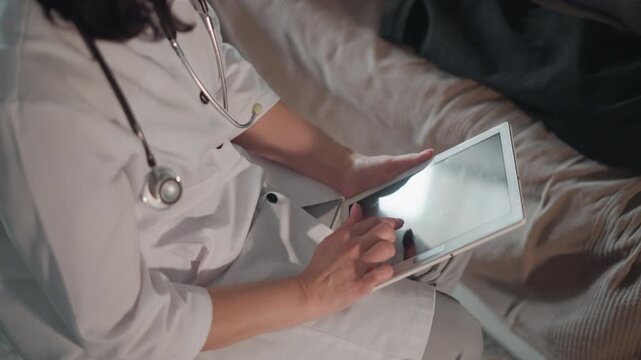 Caucasian doctor using tablet for telemedicine consult virtual patient interaction white coat and stethoscope touchscreen input secure connection home setting professional attentive digital