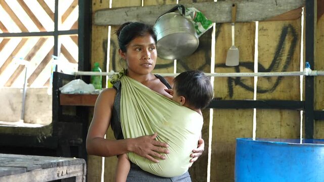 An indigenous mother from the Cab&eacute;car community in Costa Rica breastfeeding her baby in a baby carrier 
