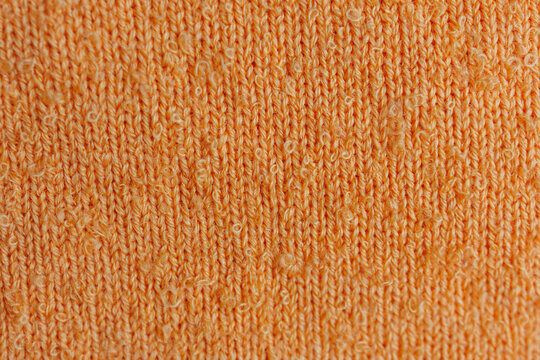Macro texture of orange knitted sweater fabric with boucle yarn loops