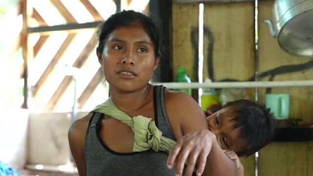 An indigenous mother from the Cab&eacute;car community in Costa Rica breastfeeding her baby in a baby carrier 