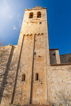 Tall historic stone bell tower against blue sky in Sant Cugat