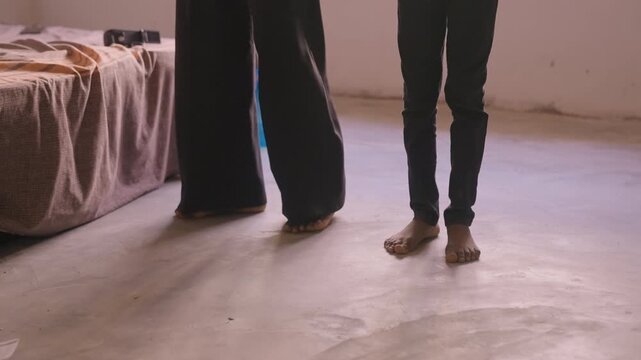 Barefoot mother and daughter dance practice on concrete bedroom floor near bed, late afternoon sunlight, playful footwork, mother guiding daughter through simple steps, warm domestic atmosphere,