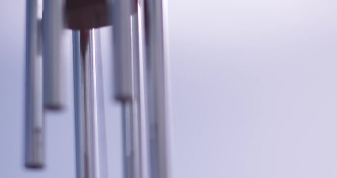 Slow motion of wind chime hanging outside blowing gently in the breeze