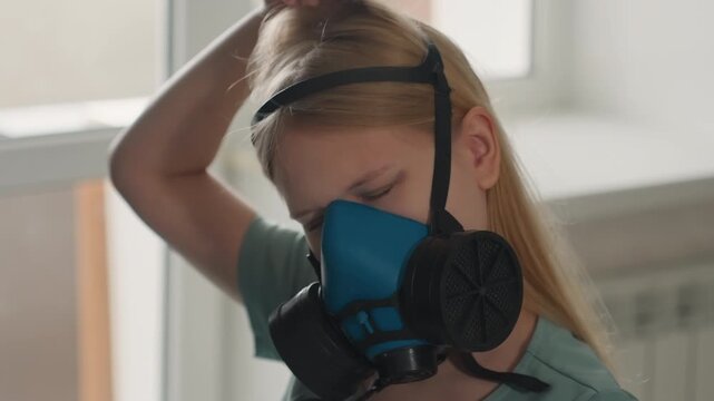 Woman adjusts respirator for inspection. Woman near window testing protective gear closely. Female individual adjusting respirator straps while observing area carefully before mold assessment