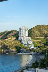Fototapeta premium Modern waterfront tower beside tropical bay and hillside