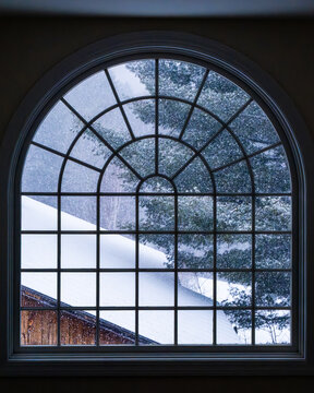 Snowy scene from inside looking out through an arched window.
