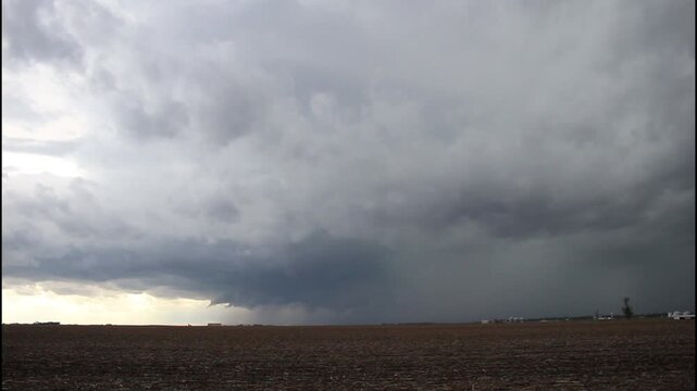A supercell thunderstorm approaches over a rural landscape.