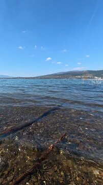 Lake water with small ripples, mountains and blue sky in background. Calm natural scenery with open landscape, daylight and clear atmosphere. Nature for travel, tourism. Poland, Europe, Lake Zywieckie