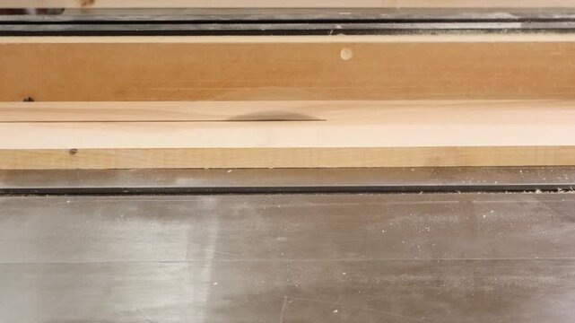 Slow motion close-up of maple face frame stock being ripped on a table saw, board-level view showing freshly cut edge and sawdust on cast iron table.