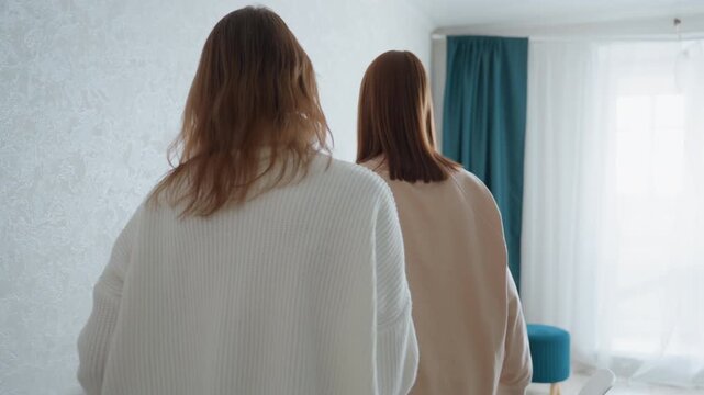 Intense feedback session with caucasian coach, two women in bright bedroom office, standing and seated shots, teacher shows blue folder, points at notes, student listens, focused eye contact, firm