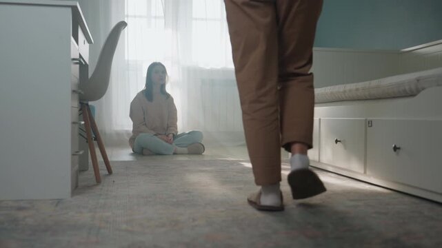 White woman student seated on floor receives book and gentle correction from home mentor in sunlit bedroom warm interior with curtain and rug, conversational reading and grammar coaching, open