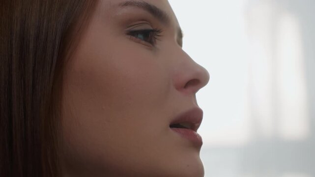 Side profile of white woman preparing speech in bright studio, poised expression and steady gaze, focused on delivery, articulation and presentation during coaching rehearsal with clean modern
