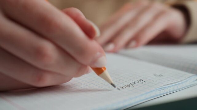 Closeup caucasian woman tutor correcting grammar exercises with pencil on grid paper, making small correction marks, steady hand, encouraging coaching vibe, home classroom corner, warm natural light