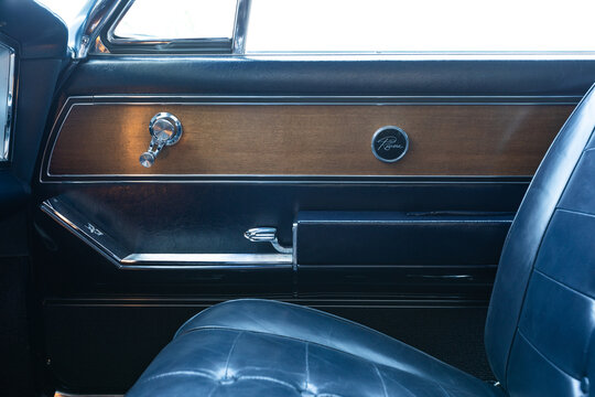 Vancouver, WA, USA - April 26, 2023 - Close up door panel of a blue 1963 Buick Riviera featuring Riviera emblem, wood grain trim, control panel, window switches, chrome accents and classic 1960s style