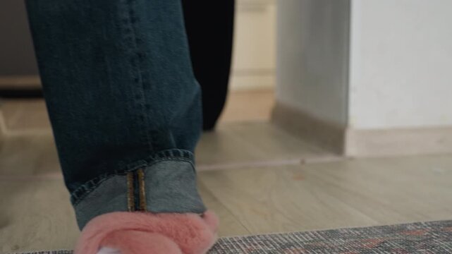 Pink slippers white socks standing close on textured rug near apartment entry toes tapping playful tension couple adjusting to move in night barefoot denim pant hem overlapping carpet intimate cozy