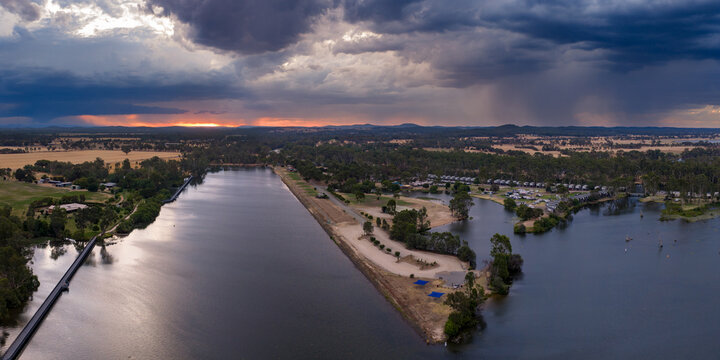 Aerial view of rain falling from dramatic storm clouds over a rowing course and inland river