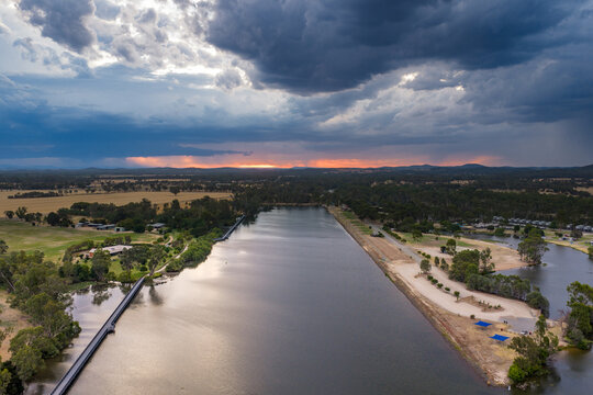Aerial view of rain falling from dramatic storm clouds over a rowing course and inland river