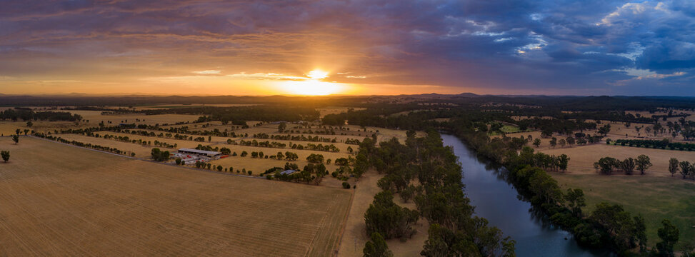 Aerial panorama view of colourful dramatic sunset over farmland alongside an inland river