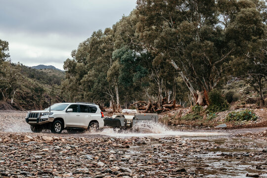 Four wheel drive crosses river bed towing camper trailer
