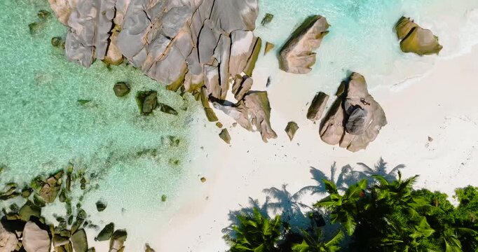 Aerial view of a white sand beach with granite rock formations and crystal-clear turquoise water. Anse Cocos. Seychelles, La Digue.