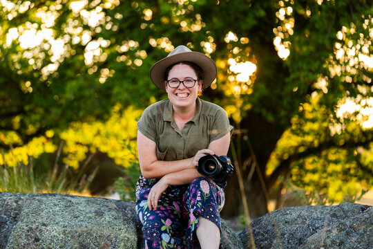 Portrait of a female photographer holding a camera outdoors at natural location