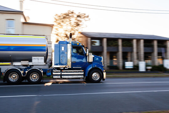 Panning image of truck driving past on country town road in sunrise light
