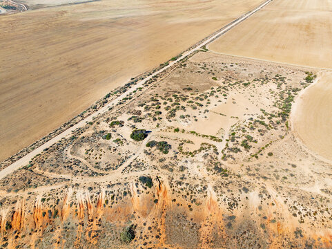 Aerial view of erosion and a long straight road though an arid landscape