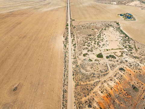 Aerial view of erosion and a long straight road though an arid landscape