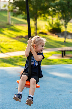 Happy little girl playing outdoors swinging on flying fox zipline at park playground