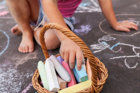 Little girl doing chalk drawing activity on driveway at home making artwork