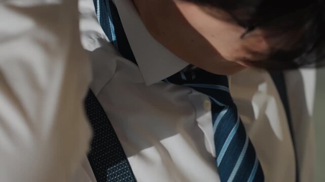 Young man adjusting tie before evening function. Male in polished outfit getting ready for night gathering. Dapper young gentleman finetuning his outfit ahead of social evening event